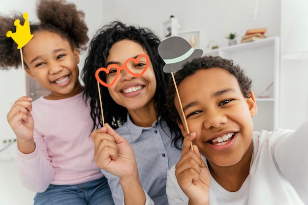 Madre sonriente tomando selfie con sus hijos en casa