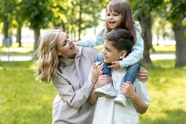 Madre sosteniendo y jugando con su hija y su hijo