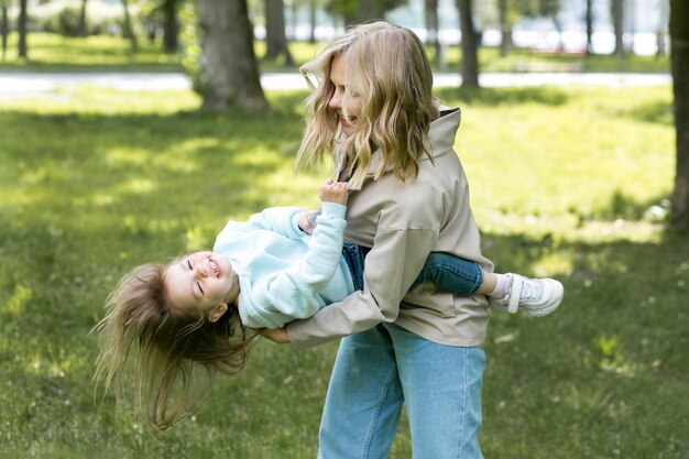 Madre sosteniendo y jugando con su hija