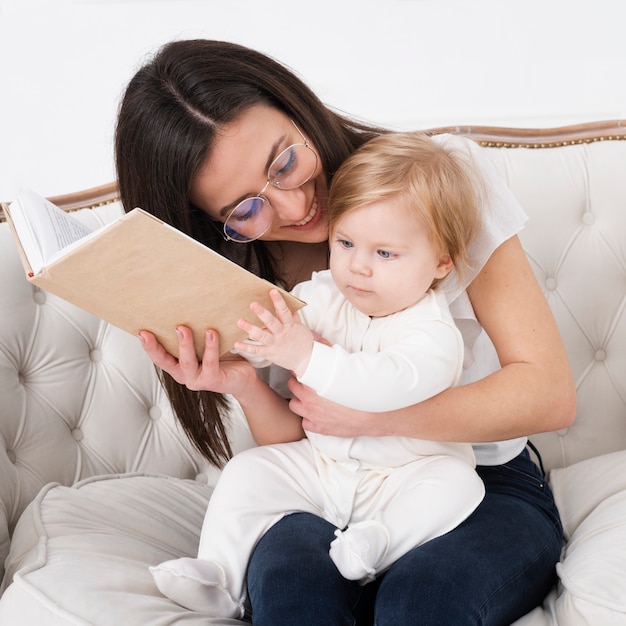 Madre sosteniendo libro y bebé