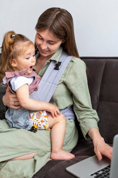 Foto gratuita madre sosteniendo niño y trabajando