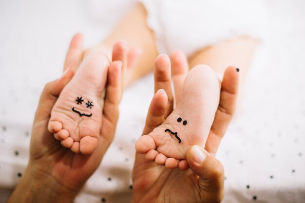 Madre sosteniendo los pies del bebé con emoticones