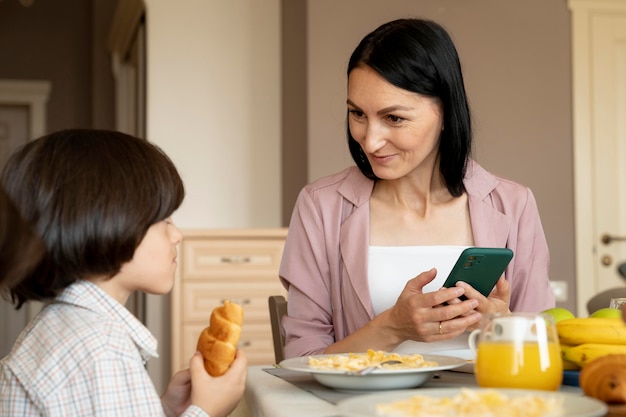 Foto gratuita madre sosteniendo su teléfono inteligente junto a su hijo