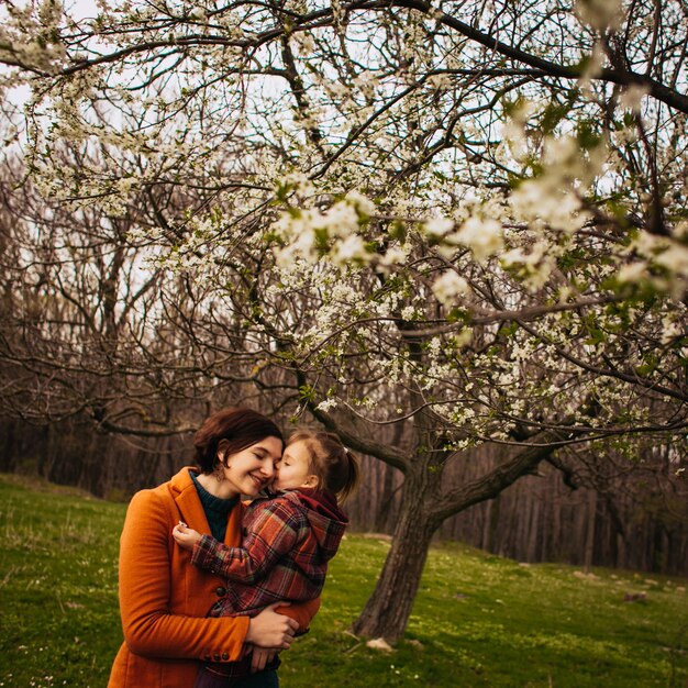 Foto gratuita la madre sostiene en las manos a su hija en el parque