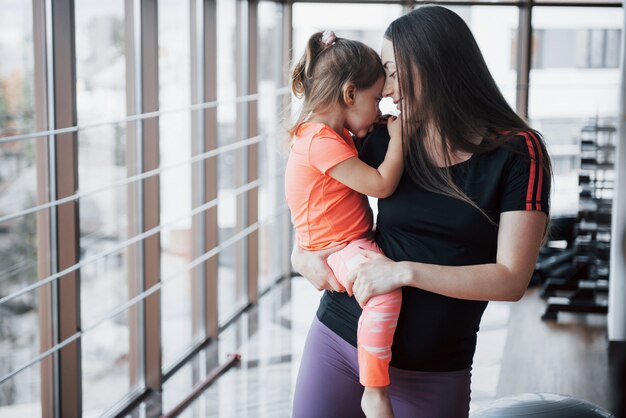 La madre sostiene a su hija en sus brazos en el gimnasio.