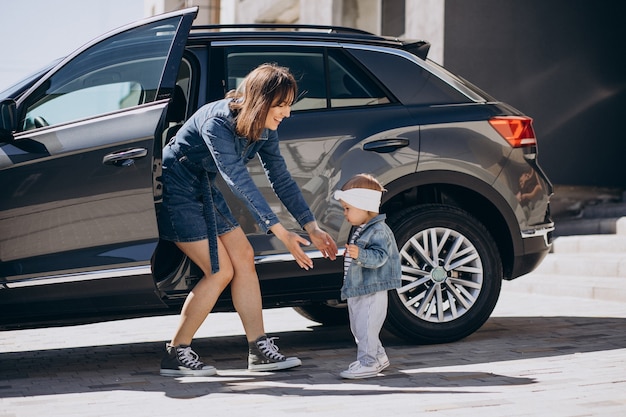 Foto gratuita madre con su bebé divirtiéndose junto al coche aparcado cerca de su casa