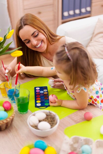 Madre y su bebé pintando huevos de pascua