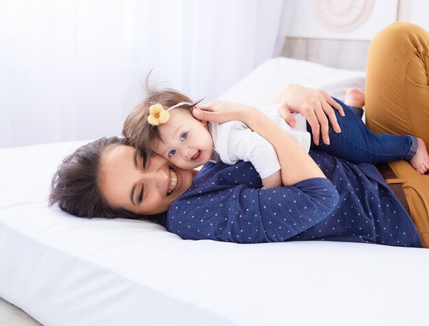 La madre con su hija se acuesta en la cama