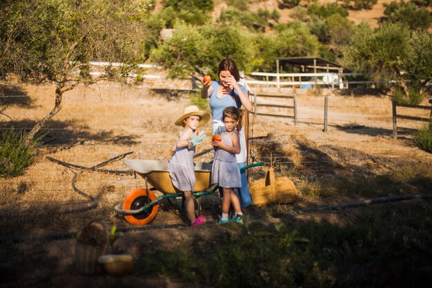 Madre con su hija dos que sostiene la manzana madura roja en el campo