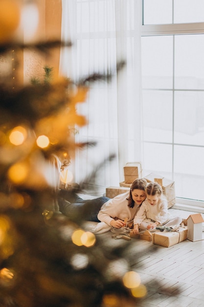 Madre con su hija empacando regalos de Navidad y divirtiéndose