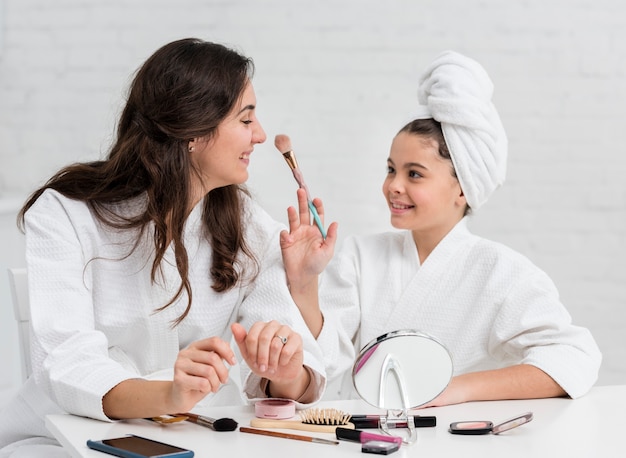 Madre y su hija haciendo su maquillaje