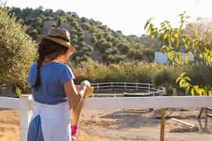 Foto gratuita madre y su hija de pie cerca de la cerca de pie en olivar