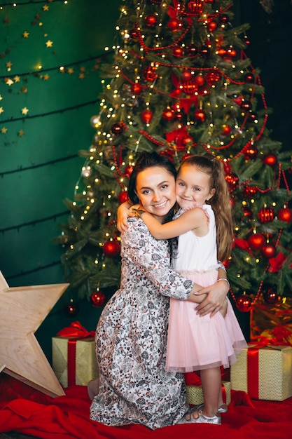 Madre con su hijita junto al árbol de navidad.