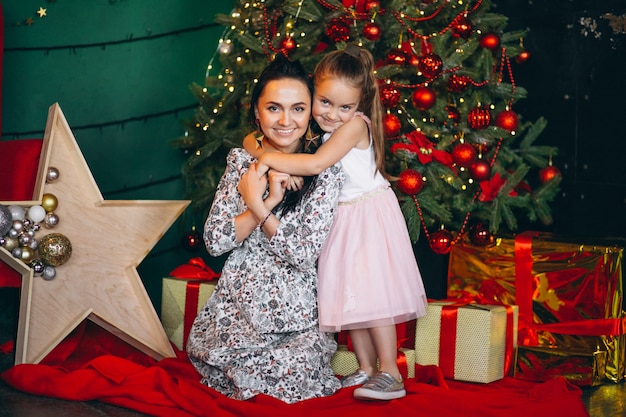 Madre con su hijita junto al árbol de navidad.