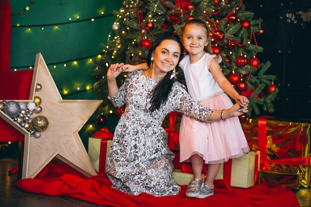 Madre con su hijita junto al árbol de navidad.