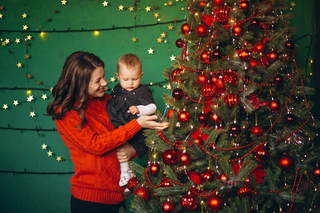 Madre con su hijita junto al árbol de navidad.