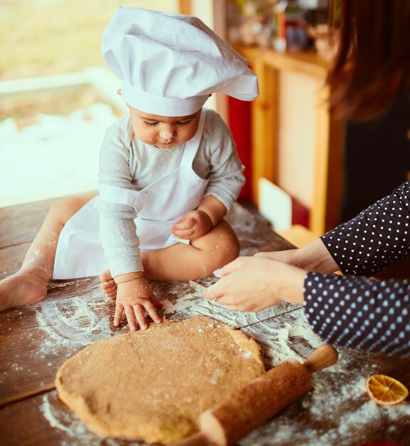 La madre con su hijo amasa la masa en la cocina