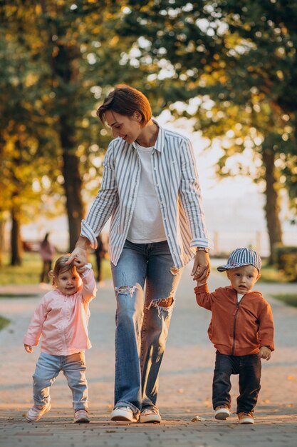 Madre con su hijo e hija en el parque otoñal