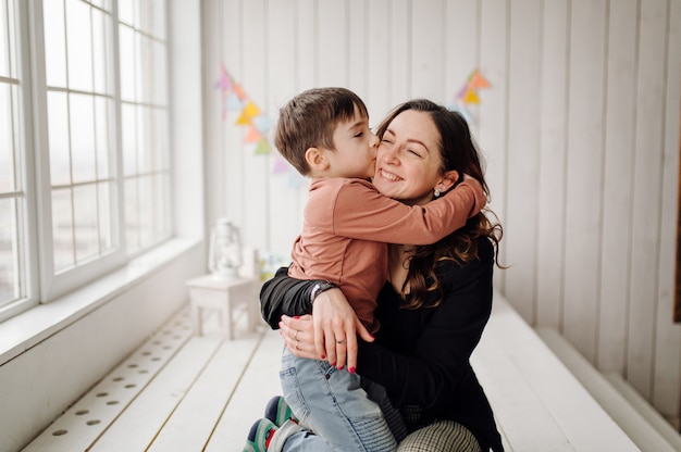 Madre y su hijo están posando en el estudio y vistiendo ropa informal.