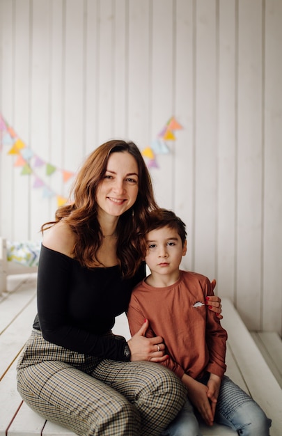 Madre y su hijo están posando en el estudio y vistiendo ropa informal.