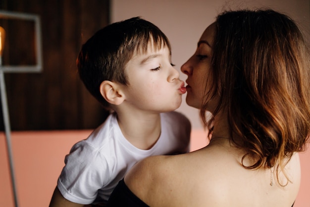 Madre y su hijo están posando en el estudio y vistiendo ropa informal.