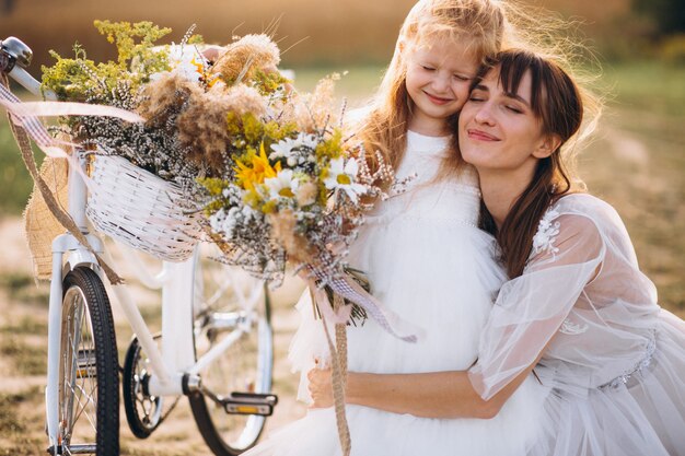 Madre con su hijo en hermosos vestidos con bicicleta