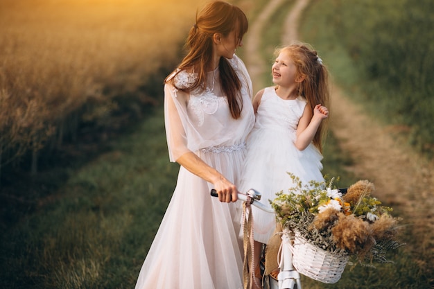 Madre con su hijo en hermosos vestidos con bicicleta