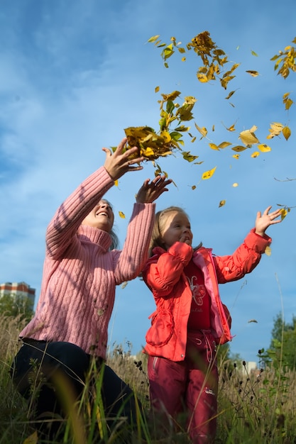 Madre y su hijo tirando hojas de arce amarillo