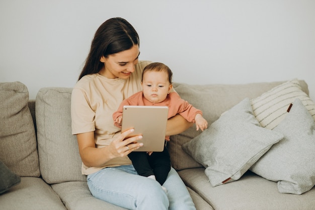 Madre con su niña bbay usando tableta en casa