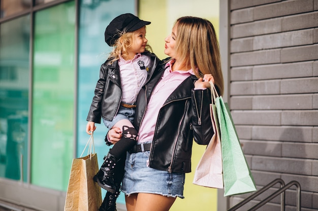 Madre con su pequeña hija linda con bolsas de compras