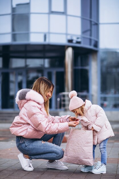 Madre con su pequeña hija linda con bolsas de compras