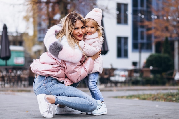 Madre con su pequeña hija vestida con ropa de abrigo fuera de la calle
