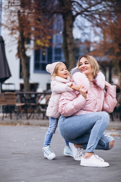 Madre con su pequeña hija vestida con ropa de abrigo fuera de la calle