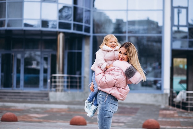 Madre con su pequeña hija vestida con ropa de abrigo fuera de la calle