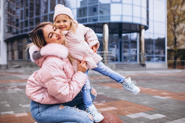 Madre con su pequeña hija vestida con ropa de abrigo fuera de la calle