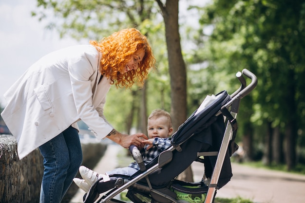 Madre con su pequeño hijo en un cochecito de bebé en el parque