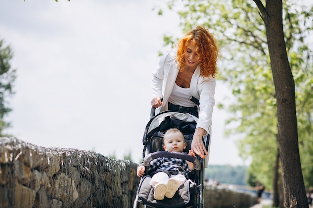 Foto gratuita madre con su pequeño hijo en un cochecito de bebé en el parque