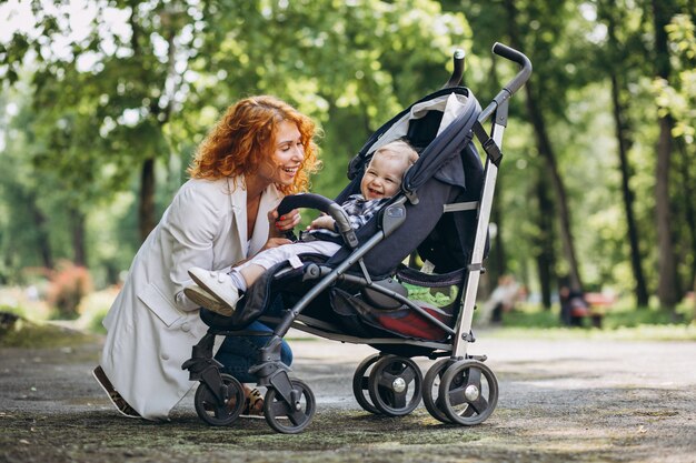 Madre con su pequeño hijo en un cochecito de bebé en el parque