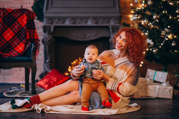 Madre con su pequeño hijo junto al árbol de navidad.