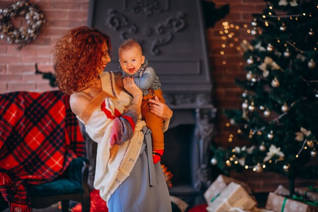 Madre con su pequeño hijo junto al árbol de navidad.