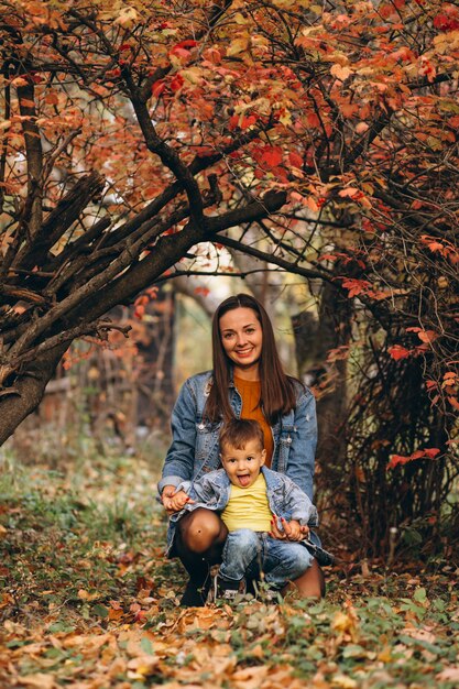 Madre con su pequeño hijo en el parque otoño