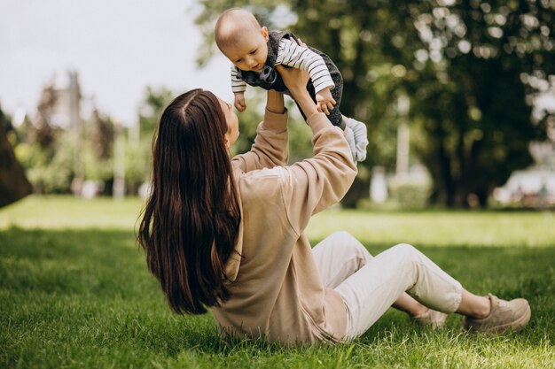 Madre con su pequeño hijo en el parque sentado en el césped