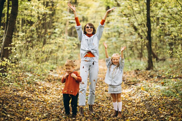 Madre con su pequeño hijo y su hija en un parque de otoño