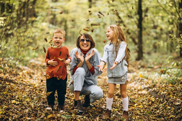 Madre con su pequeño hijo y su hija en un parque de otoño