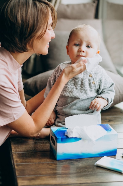 Madre con su pequeño hijo usando servilletas para secreción nasal