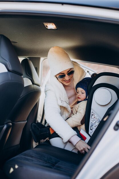 Madre sujetando a su hijo en el asiento del auto