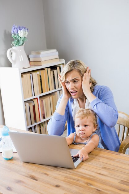 madre tensionada con la niña utilizando equipo portátil