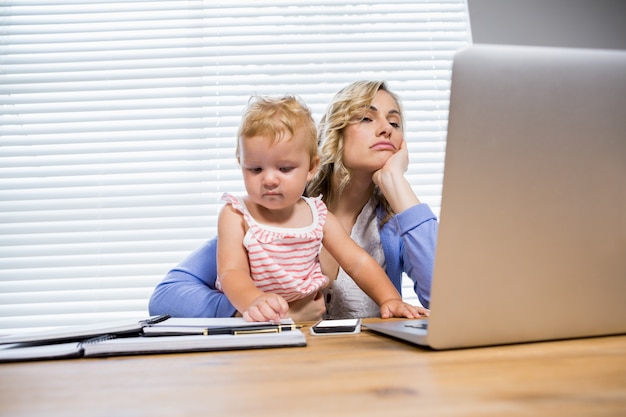 madre tensionada con la niña utilizando equipo portátil