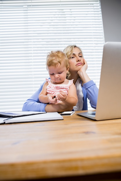 madre tensionada con la niña utilizando equipo portátil