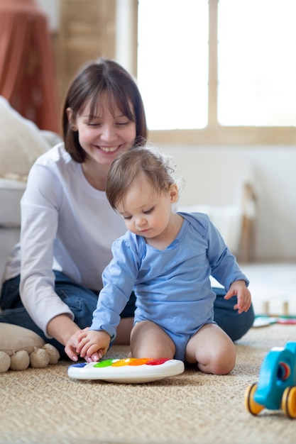 Madre de tiro completo y bebé sonriente jugando